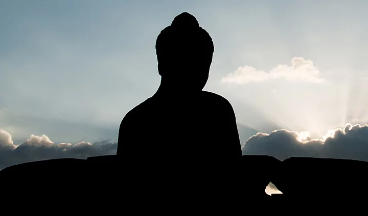 Silhouette of a person looking toward sunlight emerging from clouds