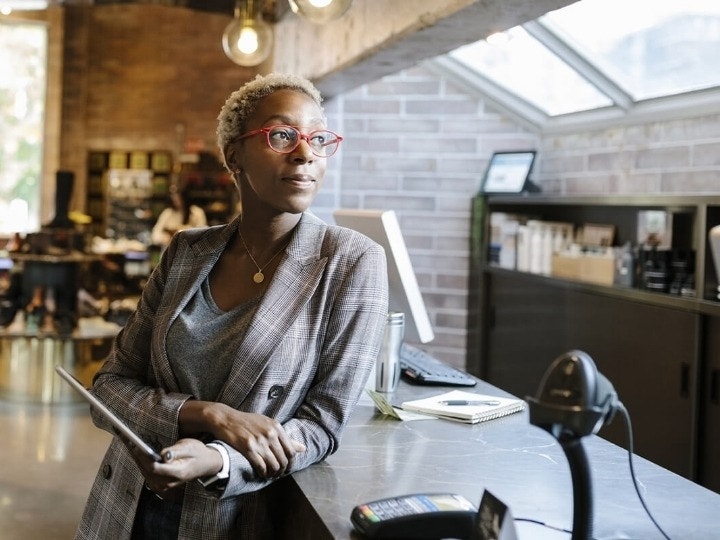 A business owner leaning on a counter while holding a tablet device