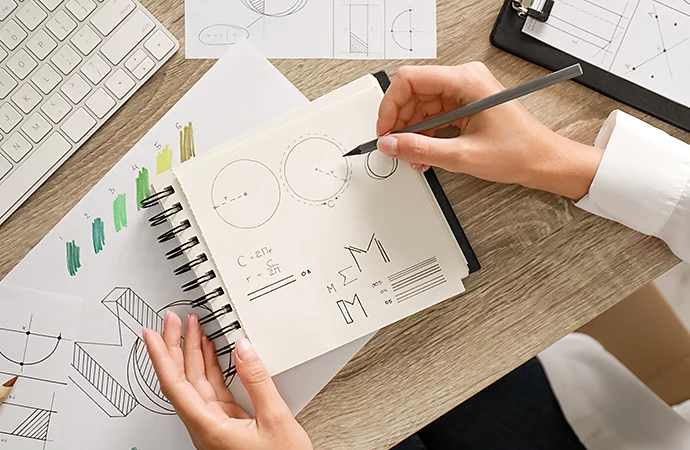 A person hand-drawing various logo designs in a notebook