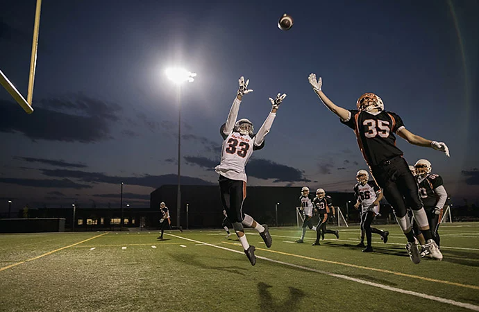 Football players jumping up to catch a football