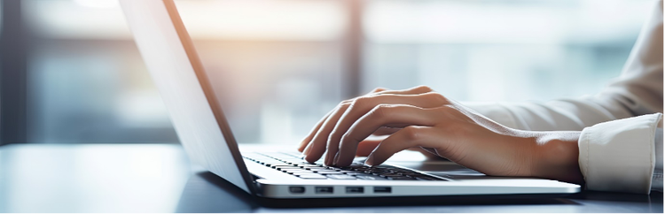 Photo of a woman's hands on the keyboard of a laptop.