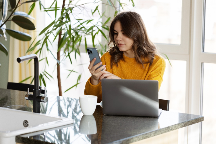 A woman sitting at a desk converts a HEIC to a PDF file on her iPhone.