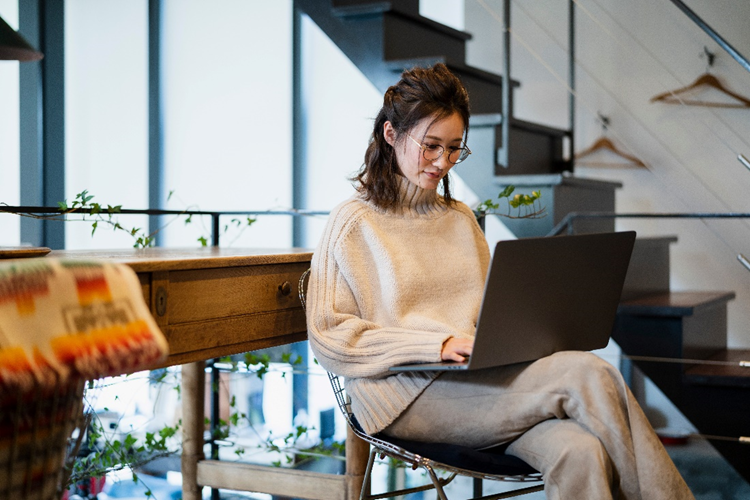 A woman uses a laptop to compress a PDF to 1MB and reduce file size.