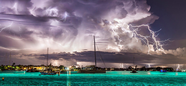 Photo of tropical lightning storm in the distance lights up the sky and sea