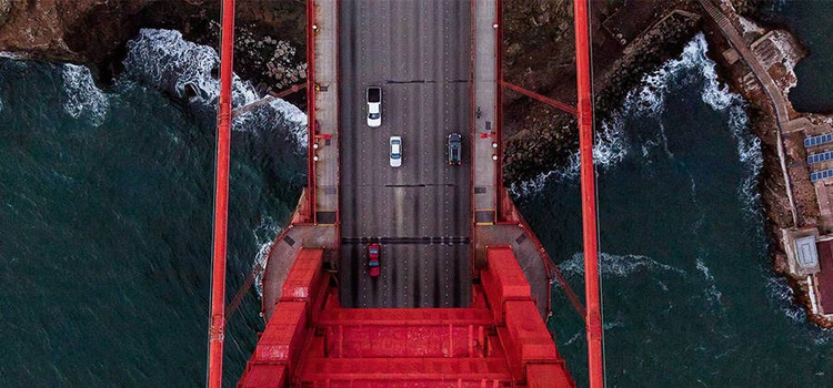 Aerial photograph captures cars going over the Golden Gate bridge.