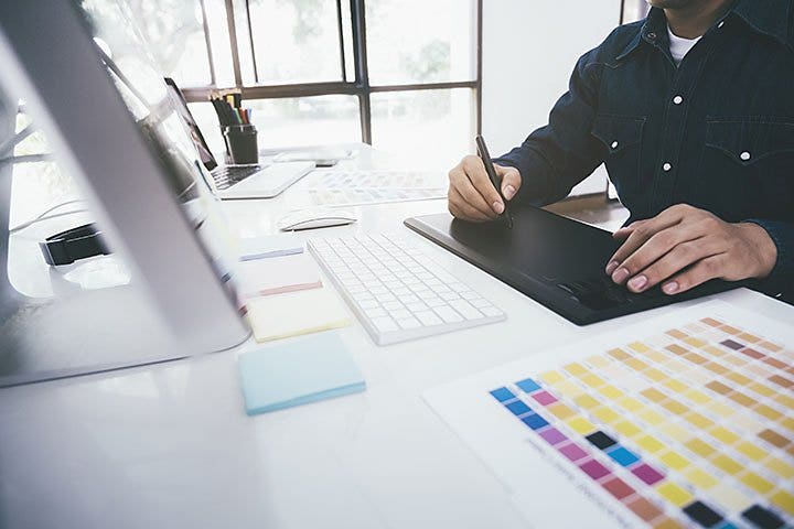 Man at desk drawing on a graphic design pad.