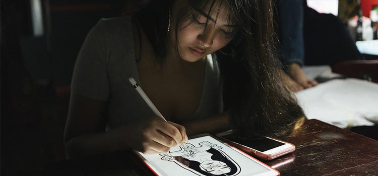 Digital artist sketching on a tablet with a digital pen.