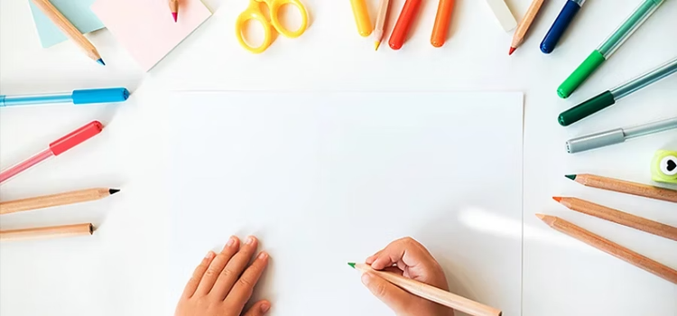 childs hands about to use coloured markers and pencils to draw