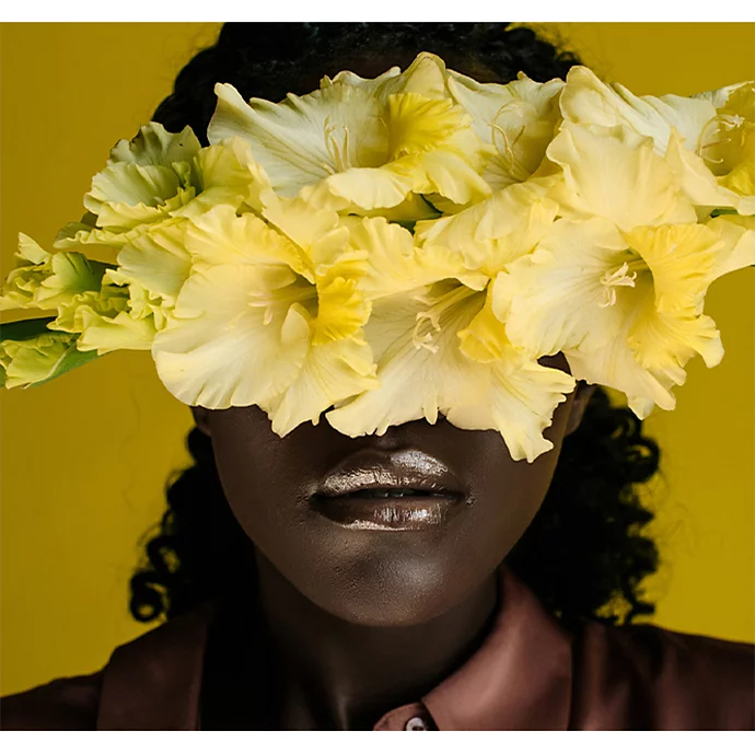 A photo of a person with a bouquet of flowers covering part of their face