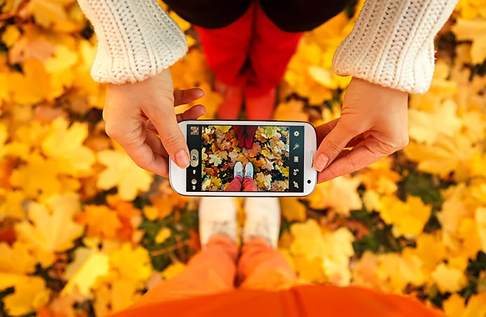 Hipsters taking photos of autumn leaves and their shoes.