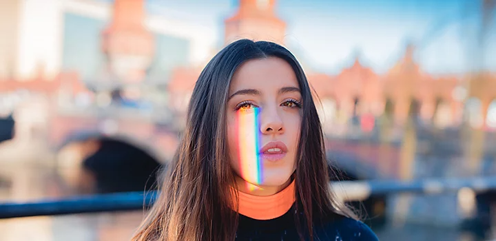 A photo of a prism reflecting a rainbow onto one side of a person's face