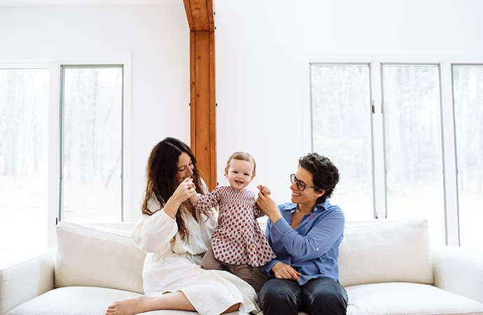 A family of three posing on the couch for a family photo