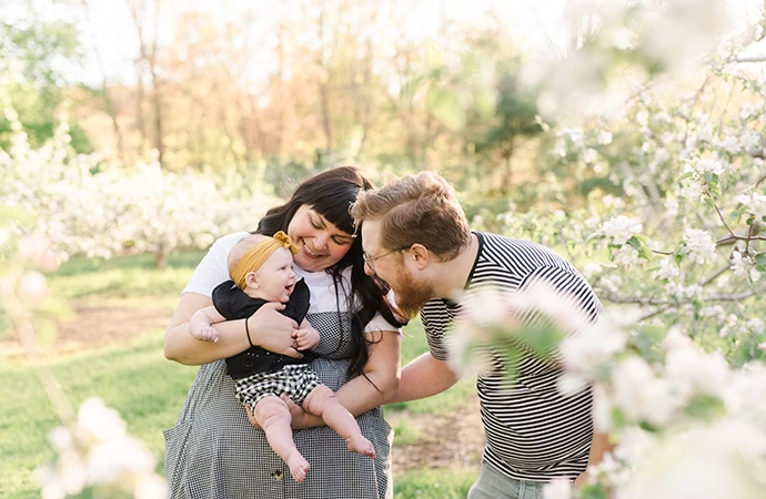 A family of three posing outside for a family photo