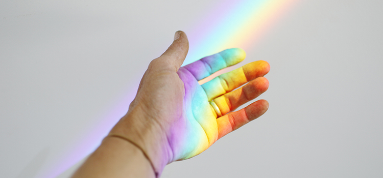 A photo of a rainbow light beaming onto someone's hand due to a prism