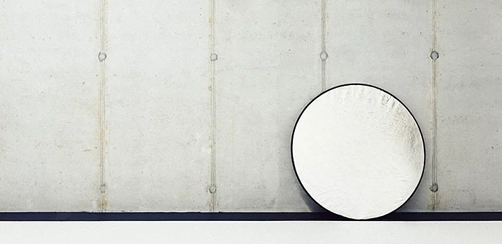 A photographer's light reflector resting against a concrete wall