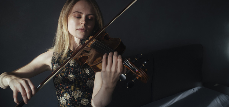 A professional headshot photo of a person playing a violin