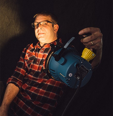 Man in a plaid shirt lighting his own creative headshot photo.