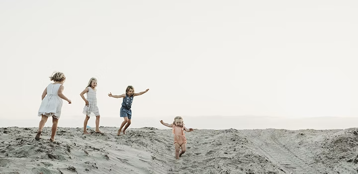 Four children being themselves on the beach for a photo