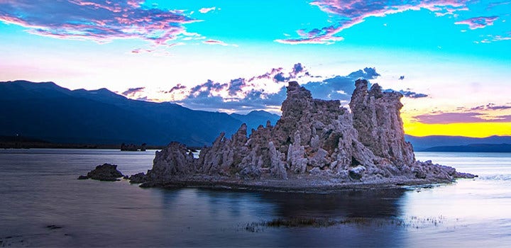 Rocky island grows dark as the sun goes down.