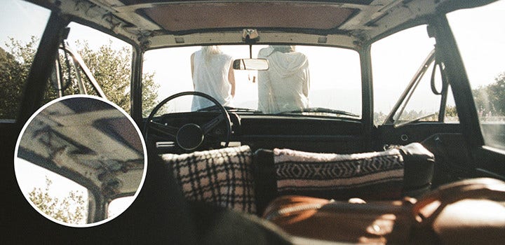 Old car interior with people sitting on the hood with film grain.