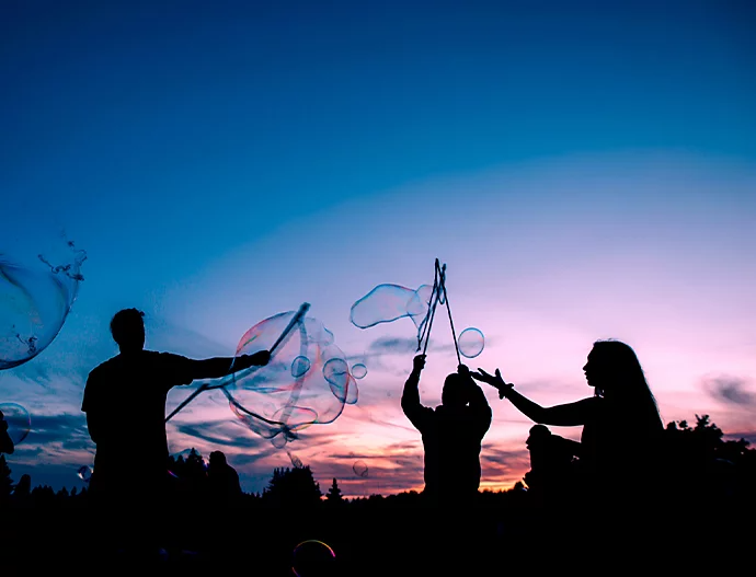 Silhouettes of people playing with bubbles at night